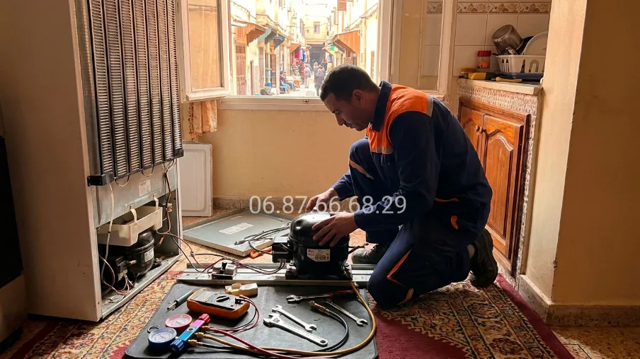 Technicien remplaçant le compresseur d'un congélateur dans la médina de Rabat — réparation sur place